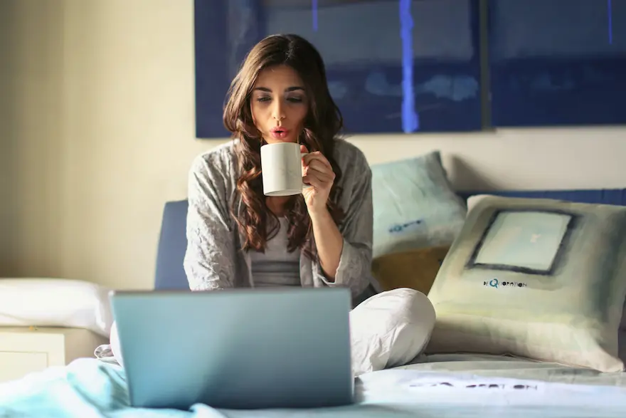 Woman looking at a laptop while drinking coffee